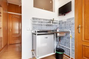 a kitchen with a sink and a tv on a wall at Double room with private bathroom and private kitchen in Barcelona