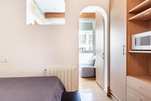 a small bedroom with a bed and a microwave at Double room with private bathroom and private kitchen in Barcelona