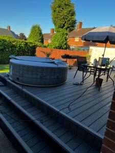 a hot tub and a table on a deck at Tranquil Gardens in Loughborough