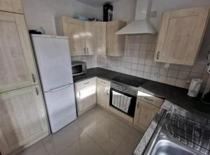 cocina con nevera blanca y fregadero en Spacious 2BDR Apartment, WIFI+ Great TV en Romford