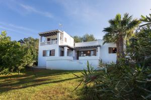 a white house with a palm tree in the yard at Casa en Ibiza con vistas increíbles en Es Figueral in Es Figueral Beach