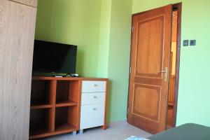- une chambre avec une télévision et une porte en bois dans l'établissement Lenke Apartmanház, à Balatonlelle
