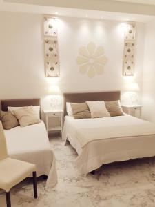 een slaapkamer met 2 bedden en een stoel en verlichting bij FLOS Guest House in Lucera