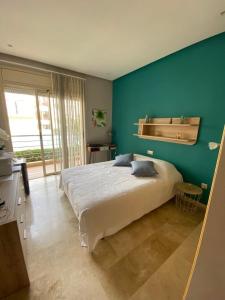 ein Schlafzimmer mit einem großen Bett und einer blauen Wand in der Unterkunft APPARTEMENT BORDURE PLAGE in Kenitra