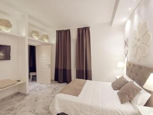 a white bedroom with a bed and a window at FLOS Guest House in Lucera