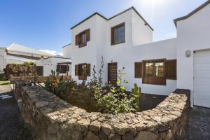 a white house with a stone retaining wall at Villa Reymar in Tías