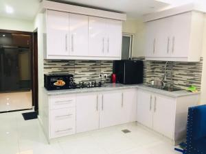 La cuisine est équipée de placards blancs et d'un réfrigérateur noir. dans l'établissement Premier Heights, à Jhelum