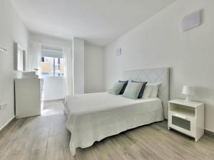 a white bedroom with a large white bed with blue pillows at La Hoya 29 Apartments in Puerto de la Cruz