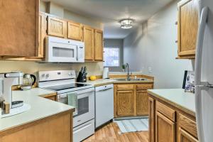 a kitchen with white appliances and wooden cabinets at Charming Anchorage Townhouse with Fire Pit! in Anchorage