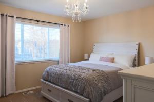a bedroom with a bed with a chandelier and a window at Charming Anchorage Townhouse with Fire Pit! in Anchorage