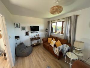 Una sala de estar con un sofá y un televisor. en Oak Valley Lodges & Camping, en Pett