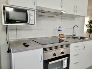 biała kuchnia ze zlewem i kuchenką mikrofalową w obiekcie La Hoya 29 Apartments w Puerto de la Cruz +37 zdjęć