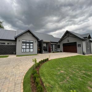 ein großes weißes Haus mit großer Auffahrt in der Unterkunft Sasavona Cottage - 349 Vaal de Grace Golf Estate in Parys