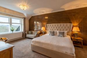 um quarto com uma cama, uma cadeira e uma janela em Lakes Hotel & Spa em Bowness-on-Windermere