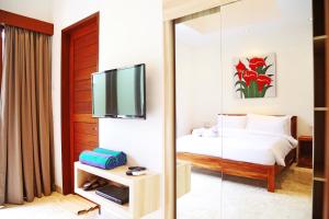 a bedroom with a bed and a tv and a mirror at Jas Green Villas and Spa in Seminyak