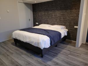 a large bed in a bedroom with a brick wall at L'appel Studio near Amsterdam in Warder