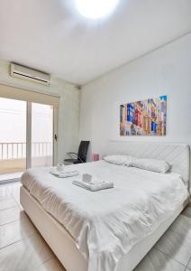 a white bedroom with a large white bed and a window at Spacious Seafront 3BR, Sliema near Beach, AC Wifi by 360 Estates in Sliema