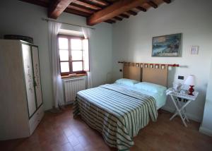 - une chambre avec un lit avec une couverture rayée et une fenêtre dans l'établissement Il Casalino, à Gualdo Tadino