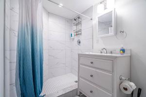 a white bathroom with a blue shower curtain and a sink at The Purple Pelican Beachfront with Ocean Balcony Unit 1 in Fort Lauderdale
