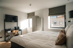 Un dormitorio con una gran cama blanca y una ventana en MyHotel Steenwijk - Giethoorn, en Steenwijk