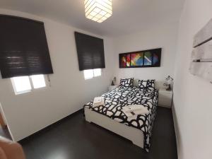 Schlafzimmer mit einem schwarzen und weißen Bett und Fenstern in der Unterkunft Apartamento Turismo Badajoz in Badajoz