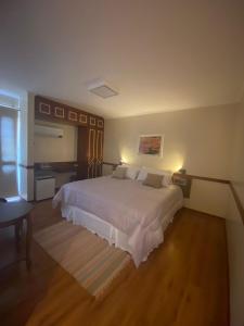 Schlafzimmer mit einem großen weißen Bett und einem Schreibtisch in der Unterkunft Hotel Marques in Araras
