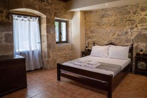 ein Schlafzimmer mit einem Bett in einer Steinmauer in der Unterkunft IOANNIS STONEHOUSE, Quiet, Privacy & Sea View. in Kissamos