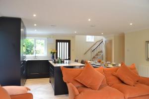 a living room with an orange couch and a kitchen at Camellia in Falmouth