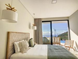 ein Schlafzimmer mit einem Bett und einem großen Fenster in der Unterkunft Noah - Private Sunset Hideaway by LovelyStay in Arco da Calheta + 36 Fotos