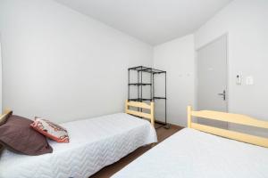 1 dormitorio blanco con 2 camas y estante en DOÑA ALZIRA, en Bombinhas