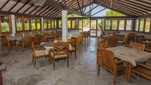 un restaurant avec des tables et des chaises en bois ainsi que des fenêtres dans l'établissement Premier Beach, à Gulhi