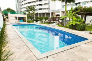 - une piscine d'eau bleue dans un bâtiment dans l'établissement Apartamento Encantador Verano na Praia, à Natal