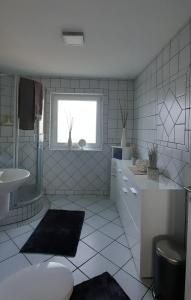 a white tiled bathroom with a sink and a window at Ferienwohnung Windhagen in Windhagen