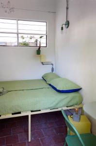 Una cama en una habitación con una almohada verde. en Youki Haus Hostel, en Montevideo