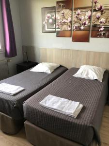 two beds in a room with paintings on the wall at La Clé des Champs in Champigny-sur-Yonne