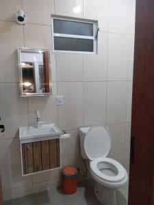uma casa de banho com um WC, um lavatório e um espelho. em Pousada Porto do Torquato em Florianópolis