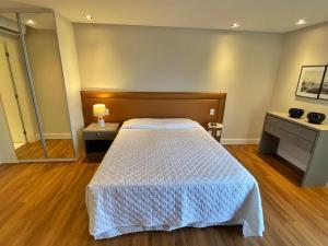 1 dormitorio con 1 cama con edredón blanco en Studio Brava Holiday, en Florianópolis
