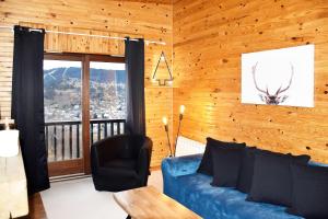 een woonkamer met een blauwe bank en een raam bij La Tanière : 4 personnes in Gérardmer