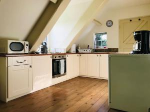 a large kitchen with white cabinets and a stove at Grove Farm Old Granary, 1st floor Loft Apartment, Includes Continental Breakfast in Lincoln