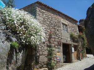 a stone building with flowers on the side of it at Taverna Lusitana in Monsanto