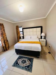 a bedroom with a large bed and a rug at GoldenWays Apartments in Mbabane