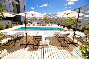 un patio con mesas, sombrillas y una piscina en Hotel Casino Talca, en Talca