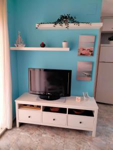 ein weißes Entertainment-Center mit einem TV an einer blauen Wand in der Unterkunft Apartamento Moncofa in Moncófa