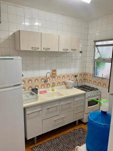 a kitchen with a sink and a stove and a refrigerator at Apartamento Ótima Localização no Guarujá-Astúrias in Guarujá