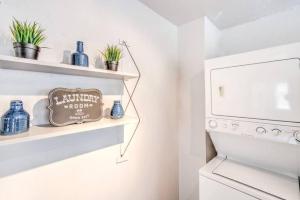 a laundry room with a washer and dryer with plants on shelves at Walk to the Best of Midtown Charming Cottage in Memphis +27 photos