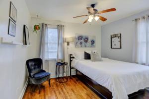 a bedroom with a bed with a ceiling fan and a chair at Midtown Cottage Walk to Overton Square in Memphis