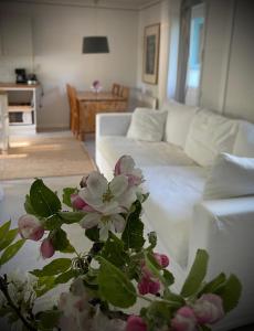 a living room with a white couch and a table with flowers at Gåsen Out in Burgsvik