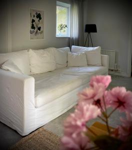a white couch in a living room with pink flowers at Gåsen Out in Burgsvik