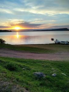 un barco estacionado en la orilla de un lago al atardecer en Casa Embalsina en Villa del Dique