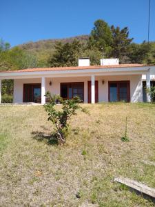 una pequeña casa en una colina con un campo de hierba en Casa Embalsina en Villa del Dique